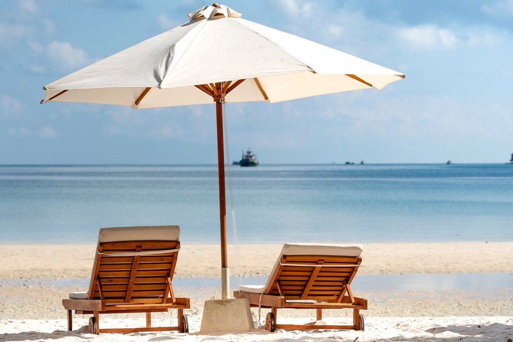 Beach umbrella with two loungers on the sand - another of the set styles used at the beach stands